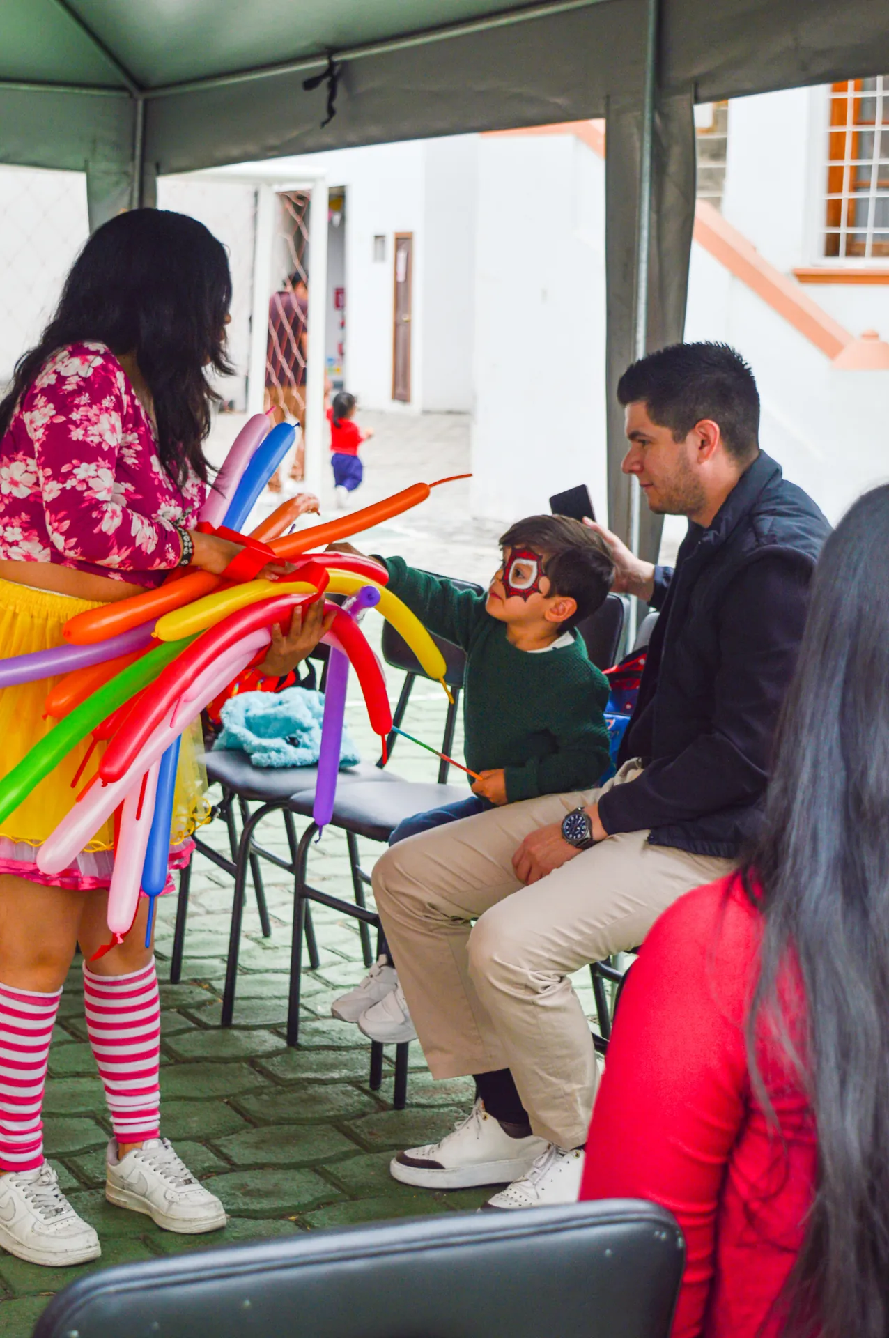 Animadora con globos de colores y niño en la celebración