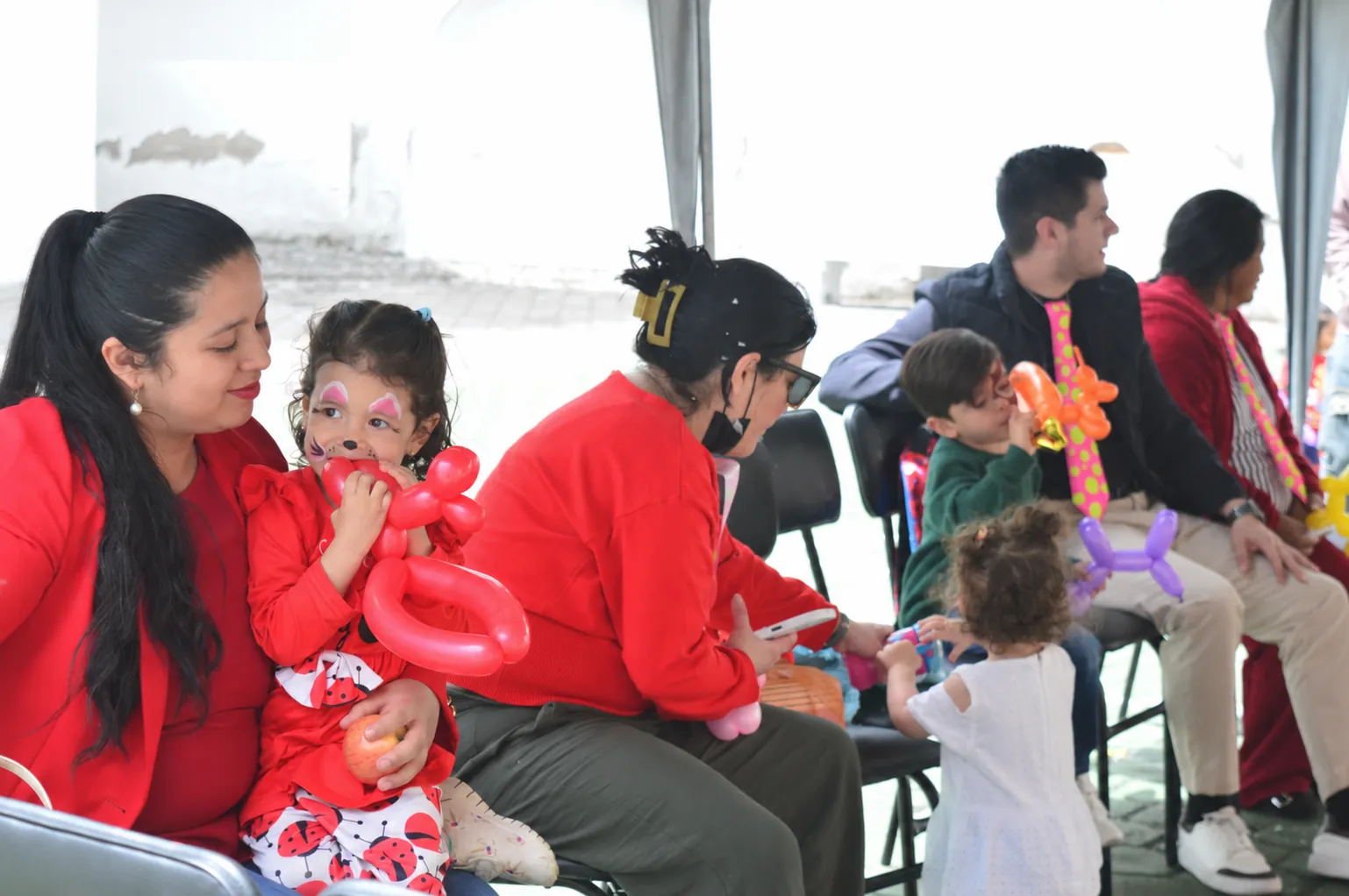 Familias sentadas con globos y pintura facial